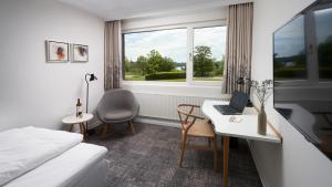 a hotel room with a bed and a desk with a laptop at Trinity Hotel og Konference in Fredericia