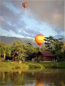 プライア・グランデにあるPousada Village dos Canyonsの水上を飛ぶ熱気球2機
