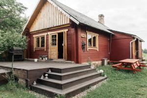 uma pequena casa vermelha com um deque e um banco em Starp debesīm un zemi em Kraslava