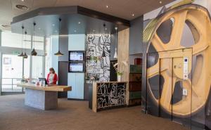 a woman sitting at a counter in a room with graffiti on the walls at ibis Poitiers Centre in Poitiers