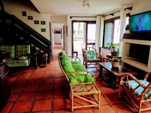 a living room with green chairs and a fireplace at Pousada Morada Da Prainha in Torres