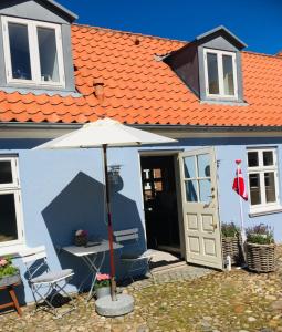 parasol siedzący przed niebieskim domem w obiekcie Harbour Living West w mieście Ringkøbing