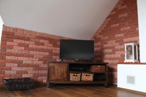 einen Flachbild-TV an einer Ziegelwand in der Unterkunft BERNAT apartman in Vrútky
