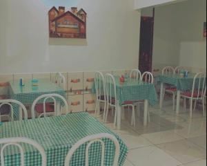 uma sala de jantar com mesas e cadeiras verdes e brancas em Hotel Maracá em Boa Vista