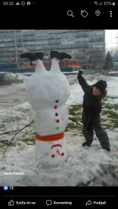 Une femme se tient à côté d'un bonhomme de neige dans l'établissement Apartman Anika, à Moravice