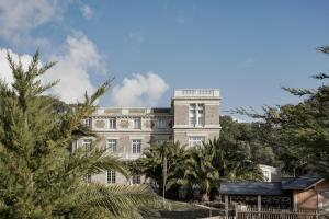 a building with palm trees in front of it at Villa Arthus-Bertrand in Noirmoutier-en-l'lle