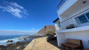 a white house with a bench next to the ocean at Casa Camilo I in Valle Gran Rey