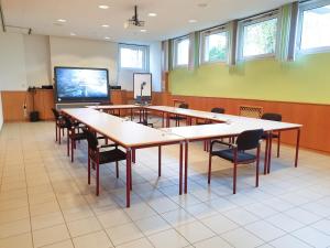 d'une salle de conférence avec des tables et des chaises et une télévision à écran plat. dans l'établissement Am Spiegeln dialog.hotel.wien, à Vienne