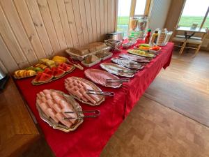 a table with a red table cloth with food on it at Hörgsland Guesthouse in Hörgsland