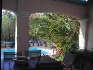 le patio في تورتور: شرفة مع طاولة و نخلة بجوار حمام سباحة