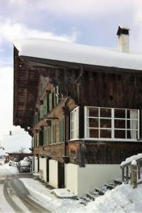 um antigo edifício de madeira com neve no chão em Apartment Adlemsried by Interhome em Boltigen