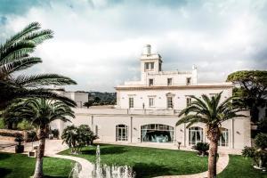 una gran casa blanca con palmeras delante en San Tommaso Hotel en Polignano a Mare