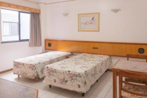 um quarto com duas camas e uma mesa e uma janela em OYO Real Palace Hotel, Teresina em Teresina