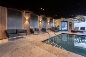 a lobby with a swimming pool with chairs and a table at Hotel Niblea Dolomites in Ortisei