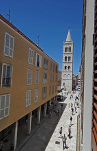 un grupo de personas caminando por una calle con una iglesia en Tinel Rooms Old City Center en Zadar