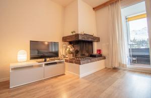 a living room with a television and a fireplace at Rothornblick 57 by Arosa Holiday in Arosa