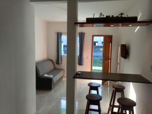 a kitchen and a living room with a bar and stools at Residencial Mar Da Galileia in Porto Seguro