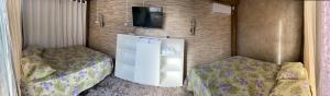 a room with two beds and a tv on a wall at Casa da Piscina Camboriú in Camboriú +12 photos