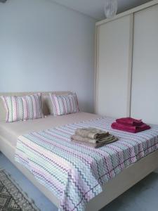 Dormitorio blanco con cama con sábanas rosas y moradas en Harmony Appartement 12 en Túnez