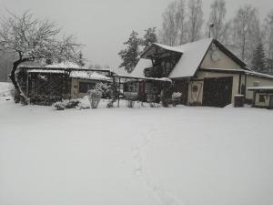 una casa cubierta de nieve en un patio en Aglonas Līdakas, en Priežmale