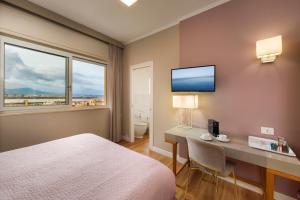 a hotel room with a bed and a desk and a window at Mercury Rooms in Cagliari