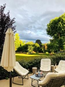 une terrasse avec des chaises, un parasol et une table dans l'établissement Le Domaine, à La Chapelle-de-Guinchay