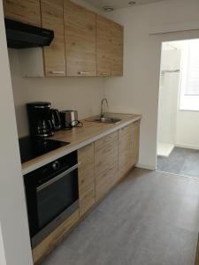 a kitchen with wooden cabinets and a sink at Appartement calme, chaleureux et lumineux in Douai