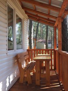 拉伊格鲁德Łabędź I Domki nad jeziorem的木凳坐在小屋的门廊上