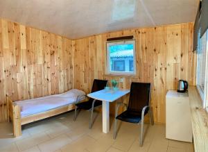 a small room with a bed and a table and chairs at Domki Nad Jeziorem I Łabędź in Rajgród