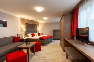 a hotel room with a bed and a couch and a television at Genusshotel Hohenbogen in Neukirchen beim Heiligen Blut