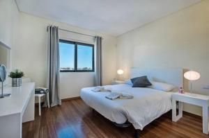 een witte slaapkamer met een groot bed en een raam bij Villa Lux - 5O in Luz de Tavira