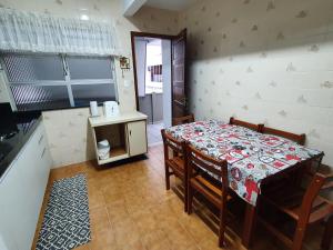 a dining room with a table and chairs and a kitchen at Casa Área Central in Balneário Camboriú