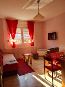 a living room with red curtains and a table at Apartman "Nina" in Soko Banja