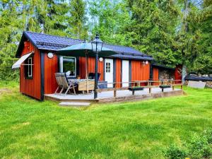 a red cabin with a deck with a table and chairs at Guesthouse at Ingarö Stockholm archipelago (breakfast) in Grönskan