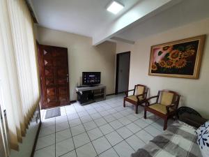 sala de estar con 2 sillas y TV en Casa Área Central, en Balneário Camboriú