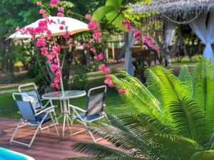 um pátio com uma mesa, cadeiras e flores cor-de-rosa em Casa de Férias em Alter do Chão-PA em Alter do Chão