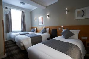 a row of four beds in a hotel room at Luna And Simone Hotel in London