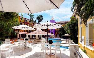 patio ze stołami i parasolami przy basenie w obiekcie Adhara Hacienda Cancun w mieście Cancún