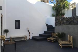 a room with stairs and chairs and a wall at Santorini Folia Cave house, 4 pers, view, jacuzzi in Pirgos