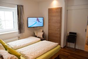 a room with two beds and a tv on the wall at Ferienwohnung Mörsbachblick in Donnersbachwald