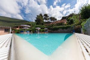 a large swimming pool with blue water and umbrellas at Vistamare La Fonte in Nisporto