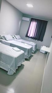 a hospital room with three beds and a window at Hotel Atlântico in Americana