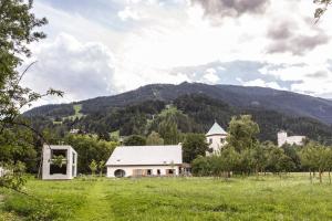 a white house in a field with mountains in the background at Iselhof in Lienz