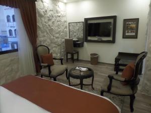 a hotel room with a bed and chairs and a television at Mount Nebo Hotel & Restaurant Madaba City Center in Madaba