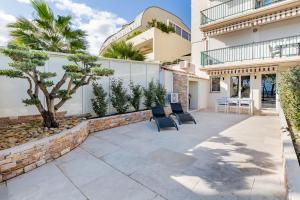 eine Terrasse mit zwei Stühlen und einem Baum vor einem Gebäude in der Unterkunft Bord de mer la Ciotat in La Ciotat