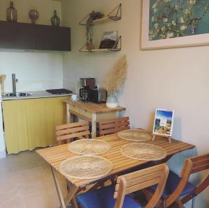 Una mesa de comedor con sillas y una cocina. en Gîte de Notre Dame, en Saint-Étienne-du-Grès