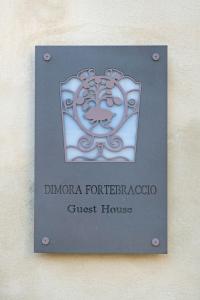 ein Schild für eine Pension an einer Wand in der Unterkunft Dimora Fortebraccio in LʼAquila