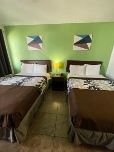 - 2 lits dans une chambre dotée d'un mur vert dans l'établissement Hwy 59 Motel Laredo Medical Center, à Laredo