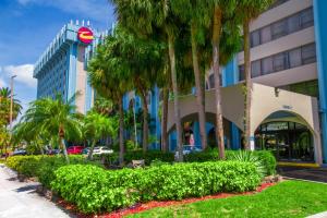 a hotel with palm trees in front of a building at Clarion Inn & Suites Miami International Airport in Miami