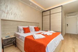 a hotel room with a large bed with orange sheets at Luxury Apartments Queen in Petrovac na Moru